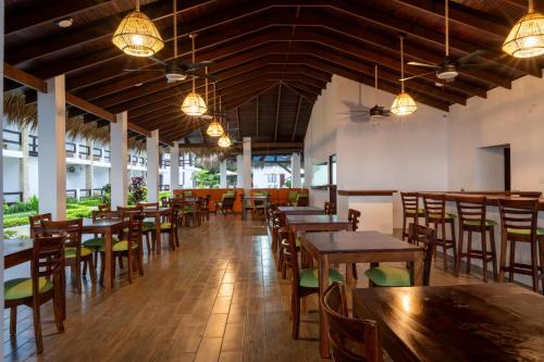 a restaurant with wooden tables and chairs and lights at Fuego del Sol Beachfront Hotel in Jacó