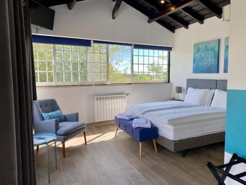 a bedroom with a bed and a chair and windows at Vida-Vi, Country House and B&B in Santa Catarina
