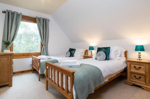 una camera da letto con due letti singoli e una finestra di Mountain View Lodge - Seasgair Lodges a Grantown on Spey