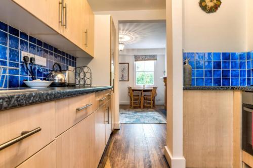 a kitchen with blue tiled walls and wooden cabinets at Upper Fisher Row in Oxford