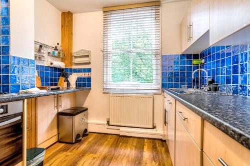 a kitchen with blue tiles on the walls and a window at Upper Fisher Row in Oxford