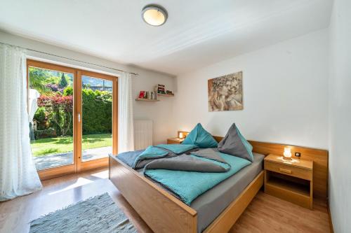 una camera da letto con un letto con cuscini blu e una finestra di Ferienhof Turmwirt Gala a Lana