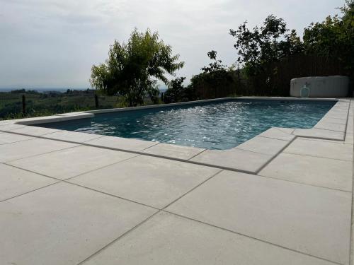 a swimming pool in a yard with a concrete floor at Agriturismo La Cà Veja in Monforte dʼAlba