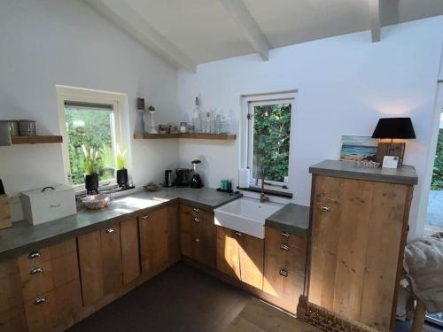 a large kitchen with wooden cabinets and a sink at Luxe bungalow in de mooie natuur! in Ouddorp