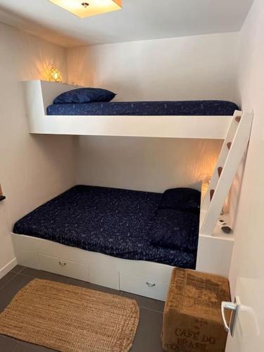 two bunk beds in a small room with blue sheets at Luxe bungalow in de mooie natuur! in Ouddorp