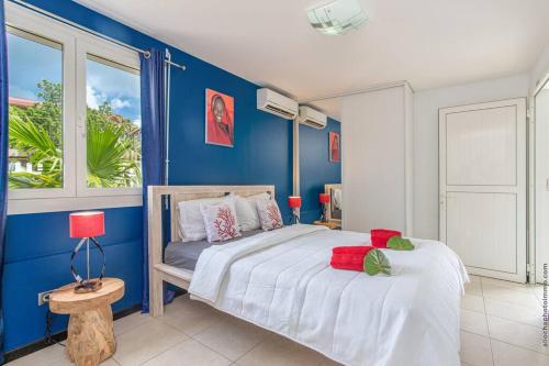a blue bedroom with a bed and a window at Villa Kaju : grande piscine et proche plage in Sainte-Luce