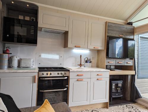 a kitchen with white cabinets and a stove at The Cuddies in Balloch