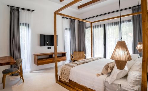 um quarto com uma cama de dossel e uma televisão em Hutan Villa by EVDEkimi Ubud em Ubud