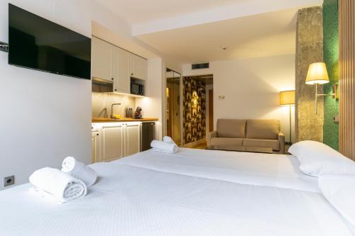 una camera d'albergo con un grande letto bianco e un divano di H-A Aparthotel Hotel Quo a Madrid
