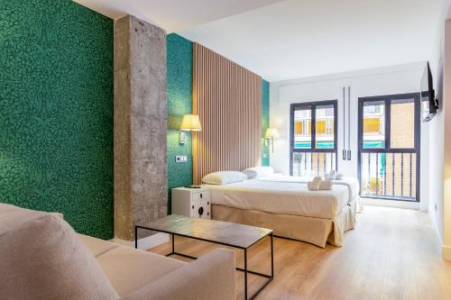 Habitación de hotel con 2 camas y sofá en H-A Aparthotel Hotel Quo en Madrid