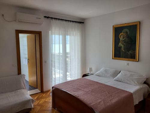 a bedroom with a large bed and a window at Apartments and rooms Iva in Pag