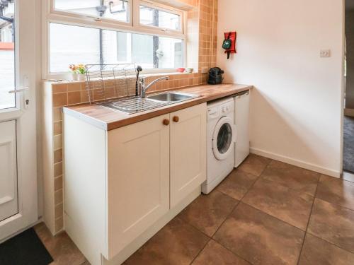 uma cozinha com um lavatório e uma máquina de lavar roupa em Gables Cottage em Northwich