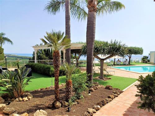 un jardín con palmeras y una piscina en Oasi del Borgo, en Borgo Bonsignore