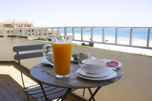 a glass of orange juice sitting on a table on the beach at Apartamento T1, Praia da Rocha - Edificio Mar Azul in Portimão