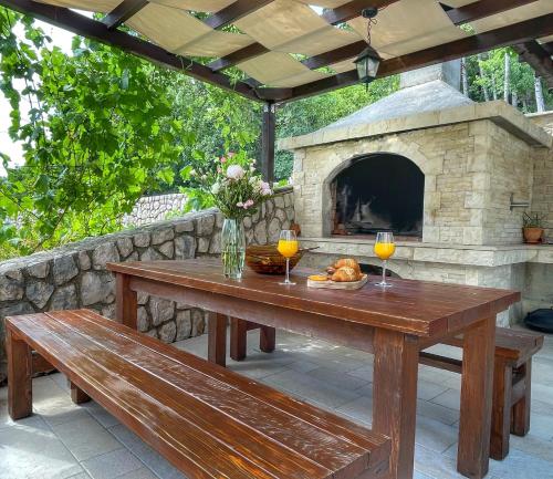 a picnic table with two glasses of wine and a stone oven at Apartments Gajeta in Povile