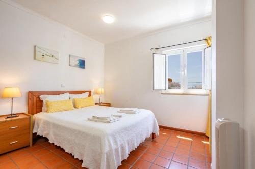 biała sypialnia z łóżkiem i oknem w obiekcie Apartamentos Atlantico by Umbral w mieście Vila Nova de Milfontes