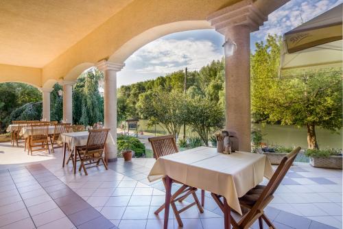 an outdoor patio with tables and chairs and an archway at Regia Panzió in Halászi