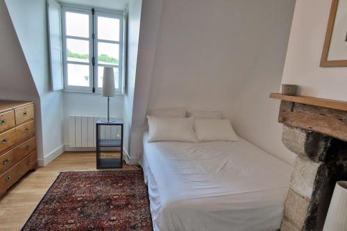 ein Schlafzimmer mit einem Bett in einem Zimmer mit einem Kamin in der Unterkunft Au cœur des remparts in Vannes