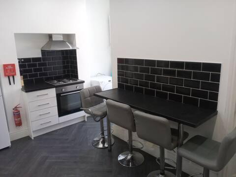 een keuken met een zwarte tafel en een aantal stoelen bij Ensuite Double-bed (E3) close to Burnley city centre in Burnley