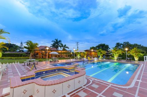 a pool at a resort with tables and chairs at Cabitat Cabañas in Quimbaya