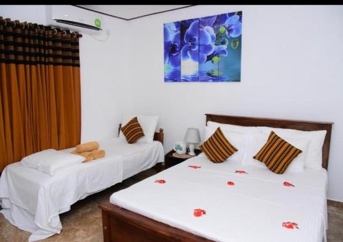 a bedroom with two beds and a painting on the wall at White Villa Airport Transit Hotel in Katunayake