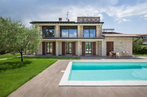 a villa with a swimming pool in front of a house at Cà Bosca in Torri del Benaco