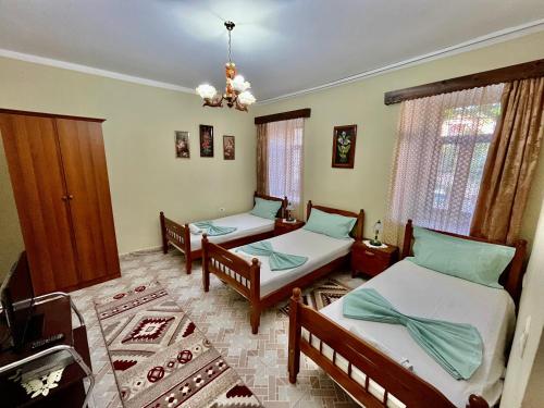 Habitación con 3 camas y lámpara de araña. en Guest House Adi Doga, en Berat