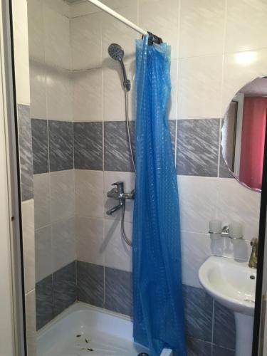 eine Dusche mit blauem Duschvorhang neben einem Waschbecken in der Unterkunft Эдем in Tscholponata