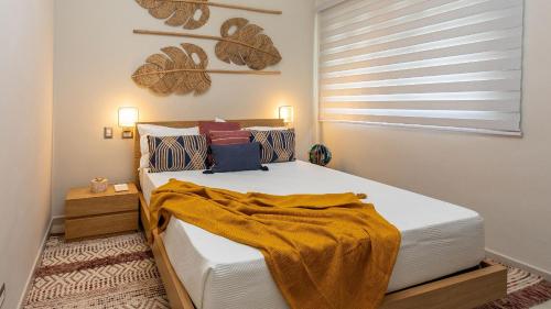 een slaapkamer met een bed met een gele deken erop bij Luxury Pool & Golf View Aptin in Hard Rock Golf PC in Punta Cana