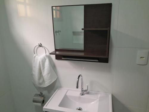 a bathroom with a sink and a mirror and a towel at Casa de Temporada Ceu e Mar in Praia do Bananal