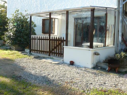 une petite maison blanche avec une terrasse couverte et une clôture dans l'établissement Location (1bis) dans un Mas avec piscine et parking, à Argelès-sur-Mer