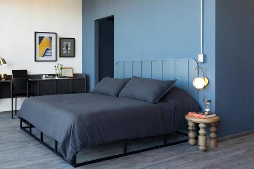 ein blaues Schlafzimmer mit einem Bett und einem Schreibtisch in der Unterkunft Loft In The Heart Of Americana, Have An Artsy Stay in Guadalajara
