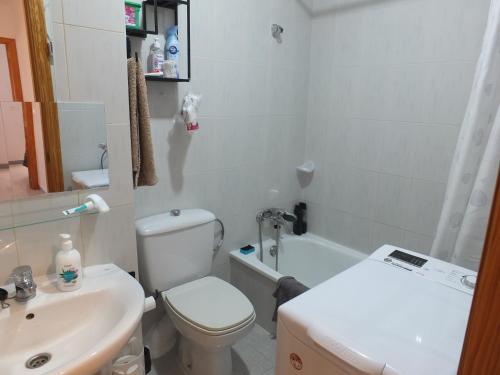 a white bathroom with a toilet and a sink at Neptuno Playa San Antonio in Cullera