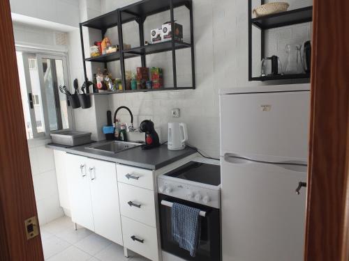 a kitchen with a white refrigerator and a sink at Neptuno Playa San Antonio in Cullera
