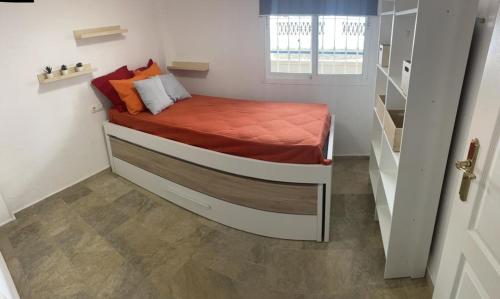 1 dormitorio pequeño con 1 cama pequeña con sábanas de color naranja en Encantador Piso con Terraza y Piscina, en Benalmádena