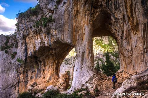 a man walking through a cave in a mountain cliff at Le Signorine Panoramic apartments in Gratteri