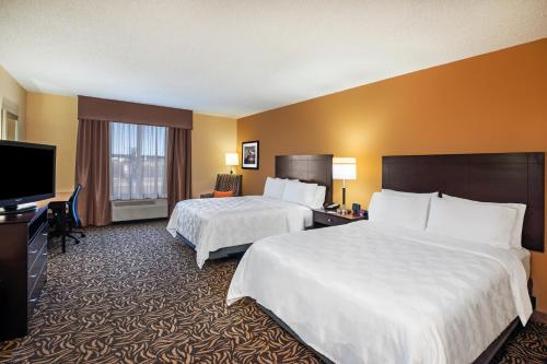 a hotel room with two beds and a flat screen tv at Holiday Inn Ardmore by IHG in Ardmore