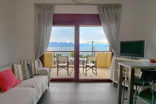 a living room with a couch and a television and a balcony at A balcony of Aegina by the saronic gulf in Aegina Town