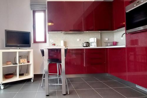 une cuisine avec des placards rouges et deux tabourets dans l'établissement A balcony of Aegina by the saronic gulf, à Égine