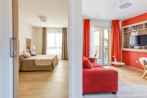 - une chambre et un salon avec un lit et un canapé rouge dans l'établissement Uzès Appart'S, à Uzès