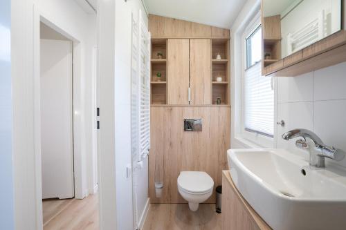 uma casa de banho com um WC branco e um lavatório. em Ostseecamp Lübecker Bucht Ferienhaus "Little Hampton" em Scharbeutz