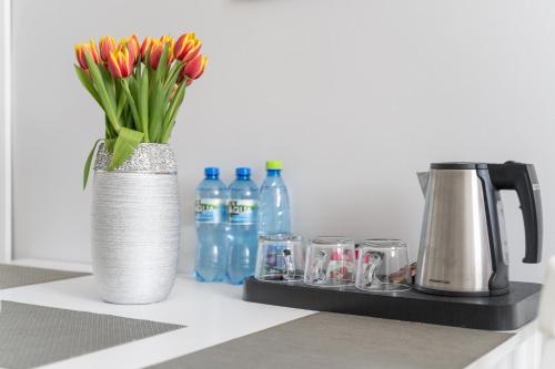 a vase with flowers in it next to glasses and bottles at Stawa Villa & Apart in Świnoujście