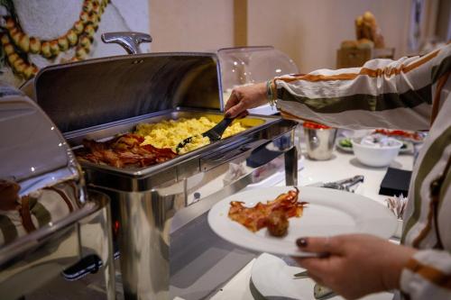 a person holding a plate of food next to a grill at Room Of Andrea Hotel in Trapani
