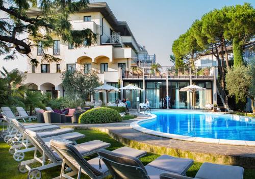 a hotel with a swimming pool and lounge chairs at Hotel Piccola Vela in Desenzano del Garda