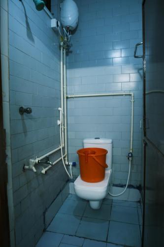 a bathroom with a toilet with a orange seat at Aum Karthikeya Residency in Chennai