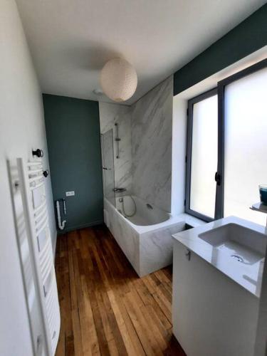 une salle de bain avec une baignoire et un lavabo dans l'établissement La Parenthèse Fléchoise, Gîte, à La Flèche