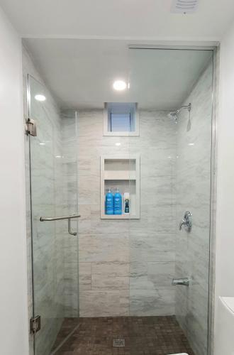 a shower with a glass door with two blue bottles at A Home Away-Deluxe Guest Room in Toronto in Toronto