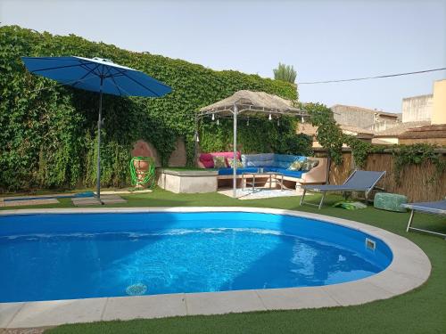 a swimming pool with an umbrella and a patio at Maison Belle Époque & suites in Oristano