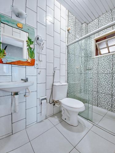 a bathroom with a toilet and a glass shower at Suítes Água Marinha in Cabo Frio