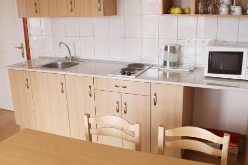 eine Küche mit einer Spüle und einer Mikrowelle in der Unterkunft Marina-Bük Apartmanház in Bük
